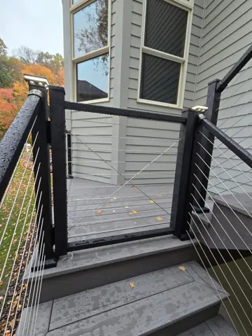 Black cable railing gate across the landing at the top of the stairs