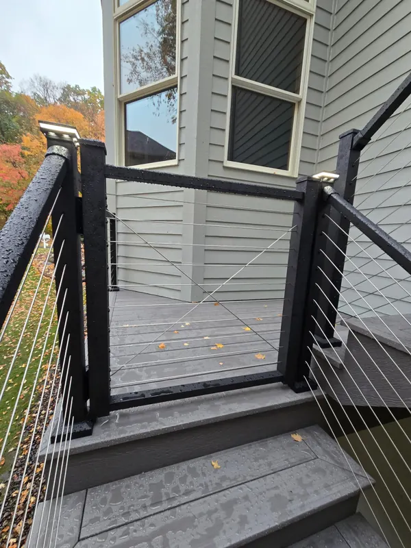 Black cable railing gate across the landing at the top of the stairs