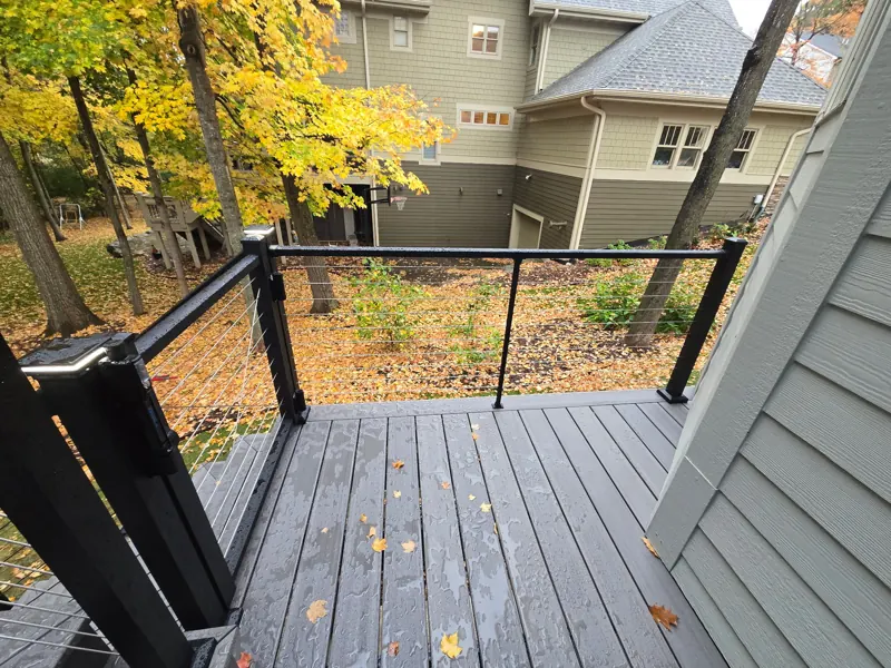 Gray deck landing with cable railings overlooking the backyard