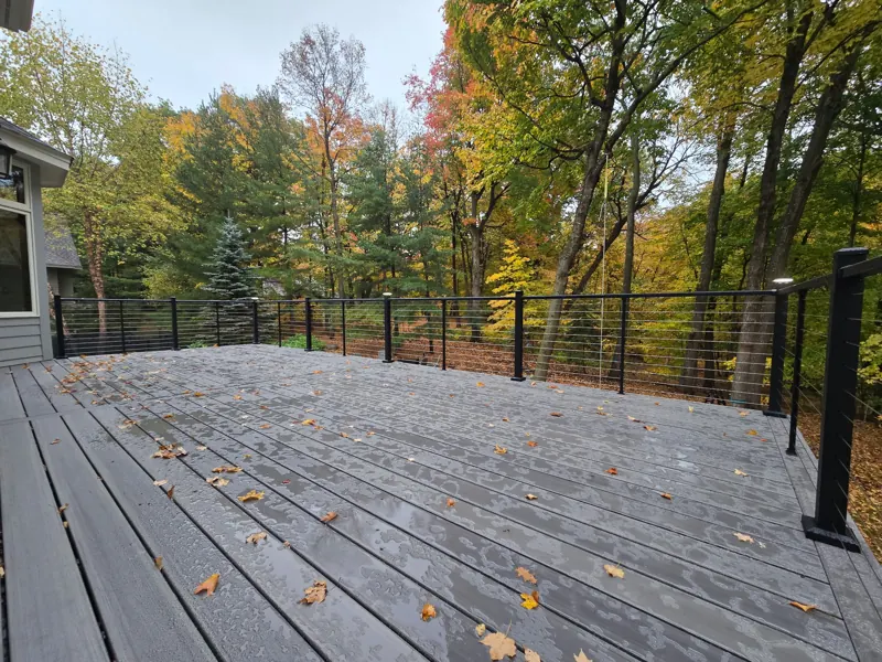 Wide gray deck surface bordered by black posts and horizontal cables