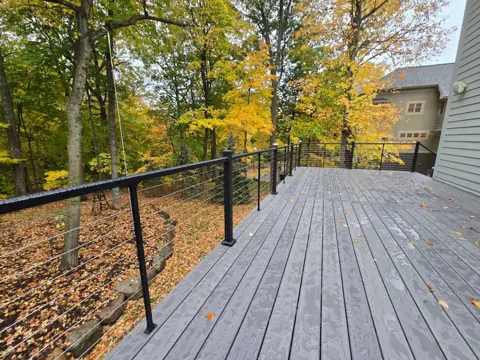 Gray deck boards running beside the house toward a wooded backyard
