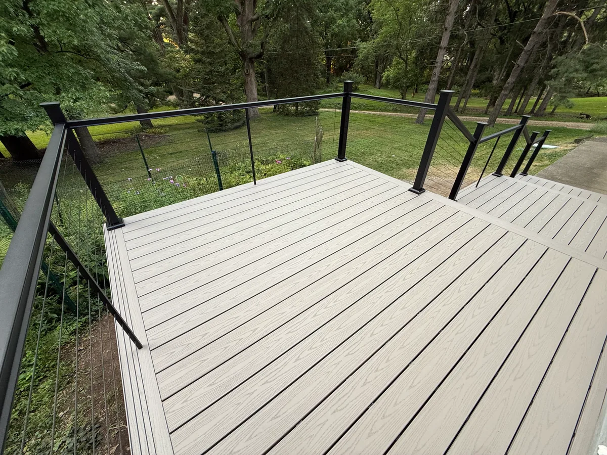 Large Cottage Grove composite deck area with black cable railings overlooking wooded yard