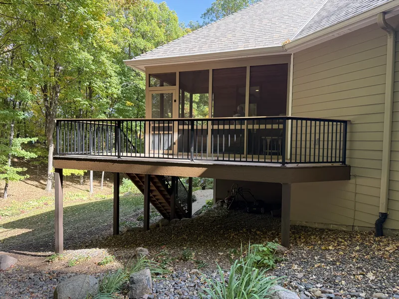 Elevated brown deck with black railings beside a screened porch in Deephaven