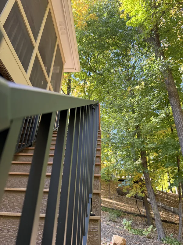 Close view of the sloped black stair railing beside the screened porch