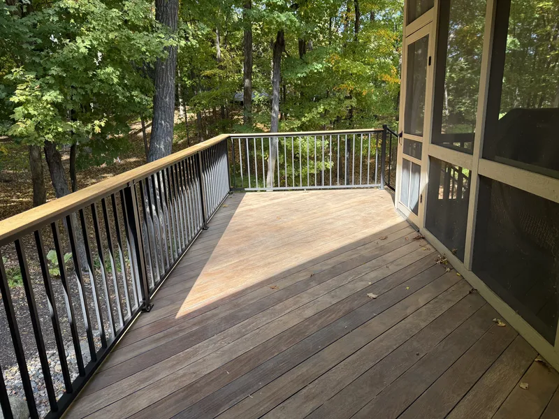 Brown deck surface and wide railing caps alongside the screened porch