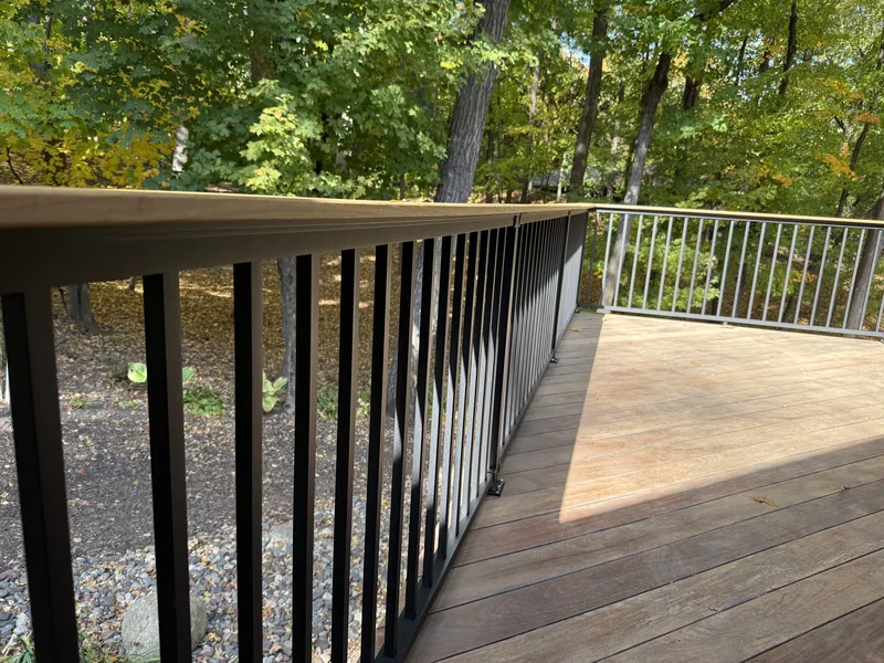 Black vertical deck balusters with a wide brown railing cap