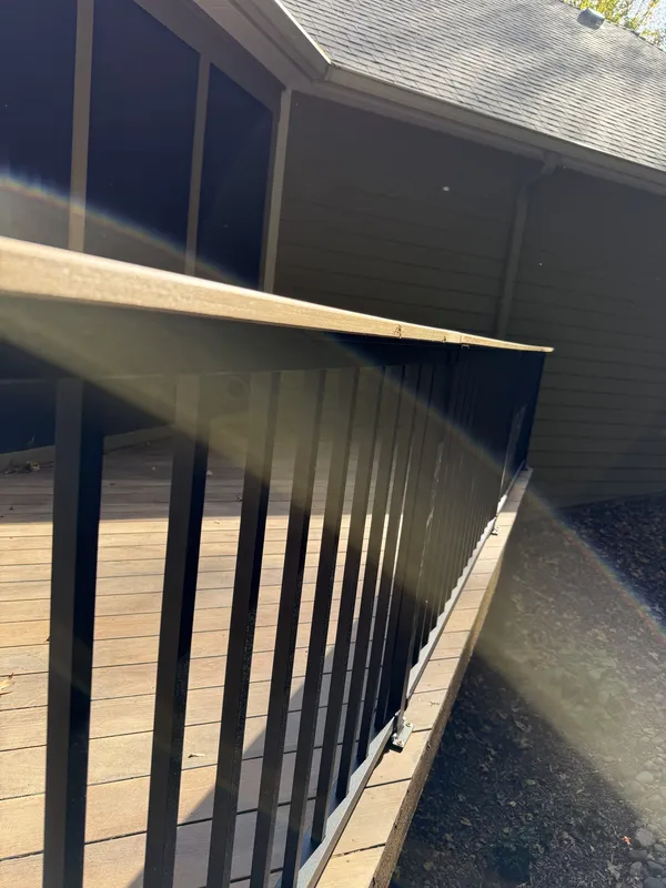 Outside view along the black deck railing beside the porch