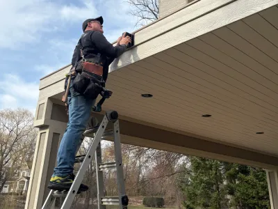 Bill working from a ladder while installing railing hardware and exterior finish details on an Edina deck