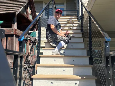 Danny in a red cap working on composite deck stairs and railing finish details