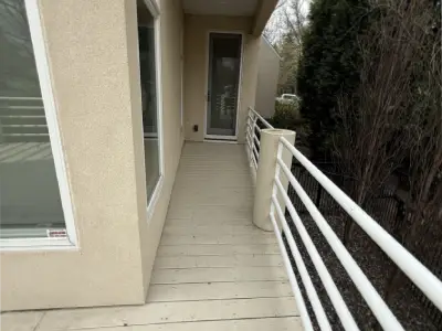 Before close view of the deck surface and white railing beside the home