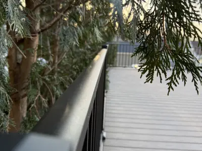 Long view down the black aluminum railing beside a completed composite garage deck