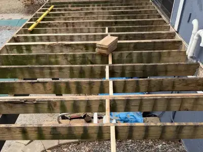 Exposed joists and framing during structural inspection for deck resurfacing in Minnetonka