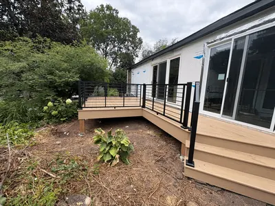 Tan composite deck and black railing system beside Minnetonka home