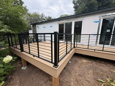 Minnetonka composite deck project with tan decking, black horizontal railings, and backyard stairs.