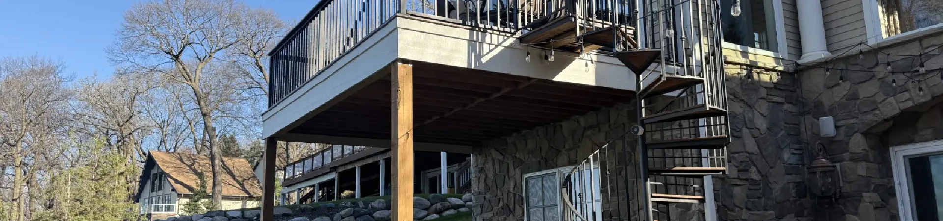 Completed deck resurfacing project in Minnetonka with composite decking, rebuilt stairs, and black aluminum railings