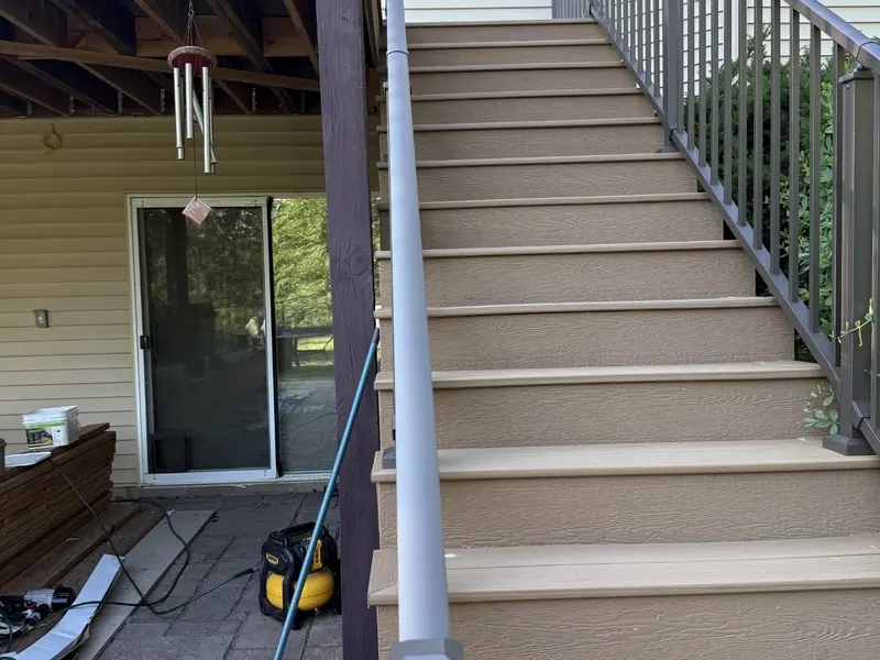 Savage composite deck staircase with warm-toned decking and dark aluminum railings