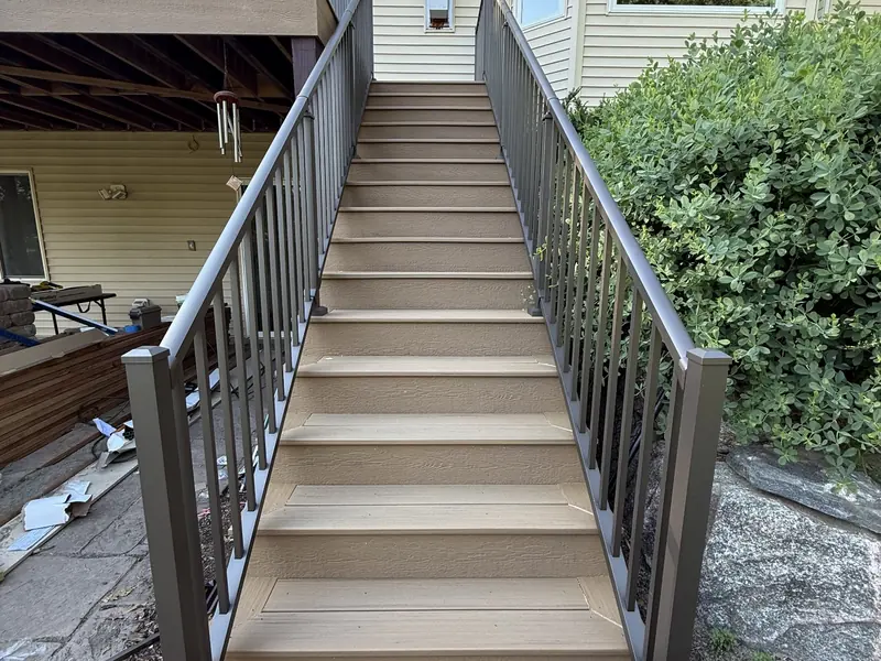 Completed Savage composite stairs with dark aluminum railings leading to the upper deck