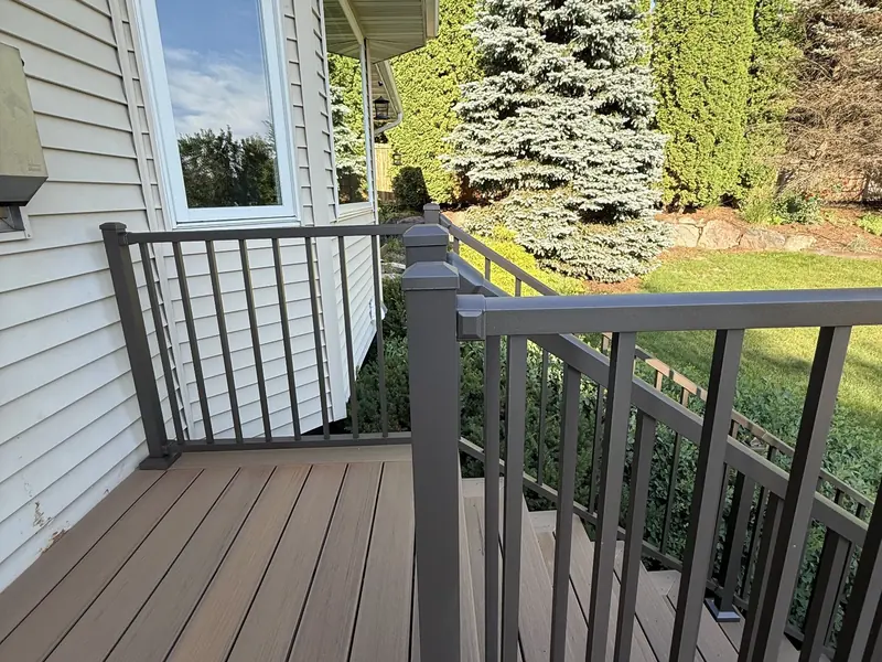 Savage composite deck landing with dark aluminum railings beside the home