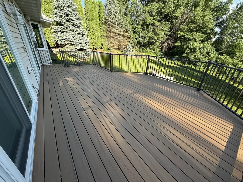 Savage composite deck project with warm-toned decking, dark aluminum railings, and a long backyard staircase.