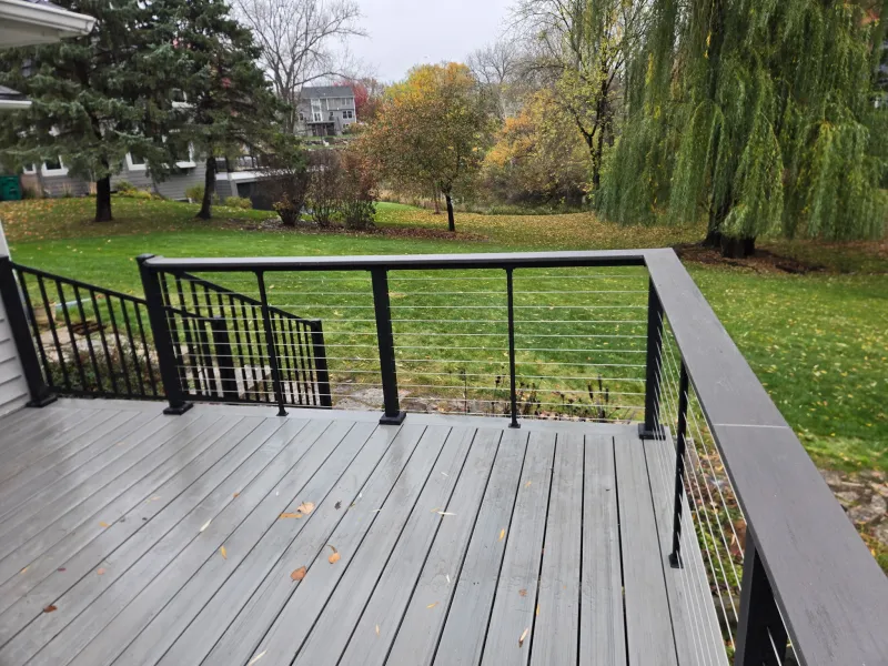 Gray deck with black posts and horizontal cable railings overlooking the backyard