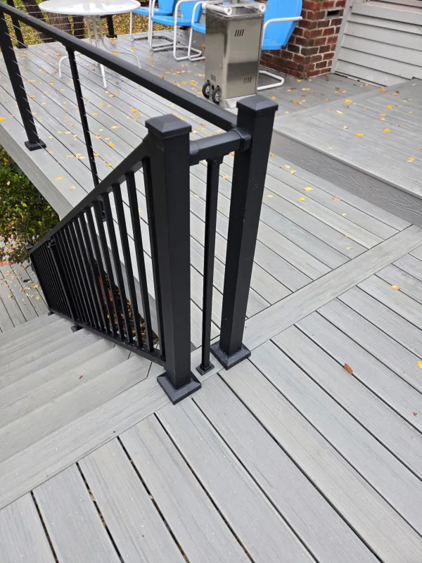 Gray deck landing beside the house with cable railings and black stair posts