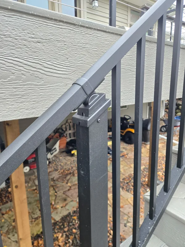 Close view of a black stair railing post and angled top rail
