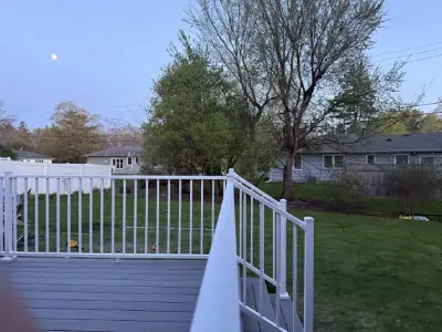 Backyard view from the completed Wayzata deck with white railing and evening sky