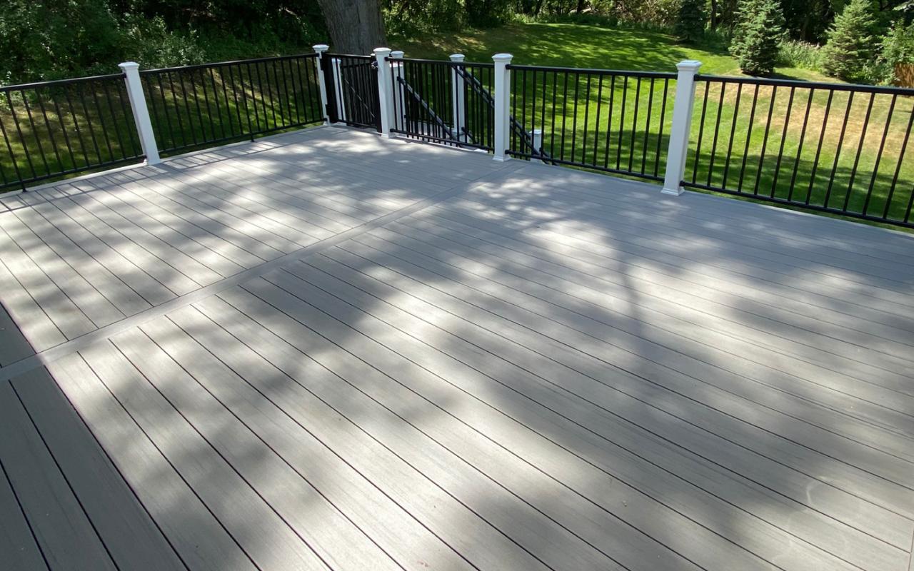 Custom composite deck with black railing overlooking a wooded backyard