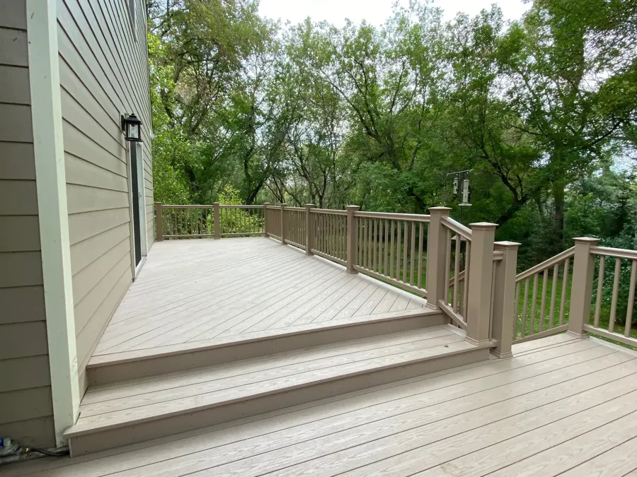 Completed deck boards, railings, and wide steps beside the house