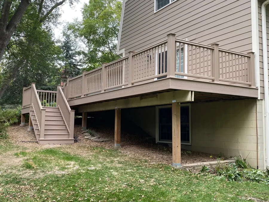 Finished raised deck with railings and a staircase beside the home