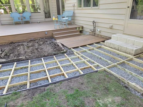 Deck framing and gravel foundation preparation during backyard deck construction