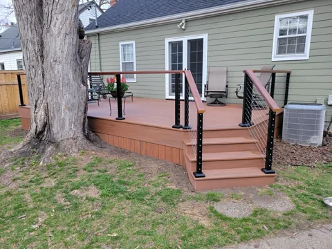 Finished composite backyard deck with cable railing and centered stairs