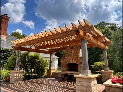 Custom wood pergola and outdoor fireplace on stone patio