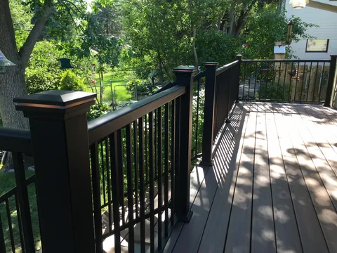 Black deck railing and post detail with green backyard beyond