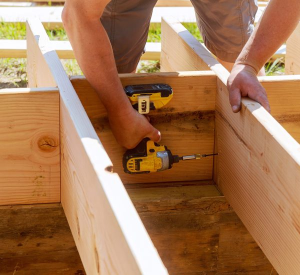 Full length of carpenter drilling wood at construc